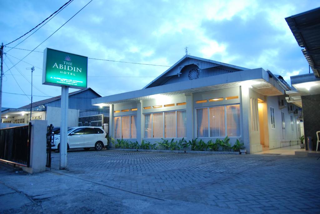PadangThe Abidin Hotel Syari'ah的前面有标志的建筑