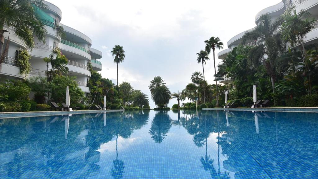 华欣Hua Hin Beachfront Condo的棕榈树建筑前的大型游泳池