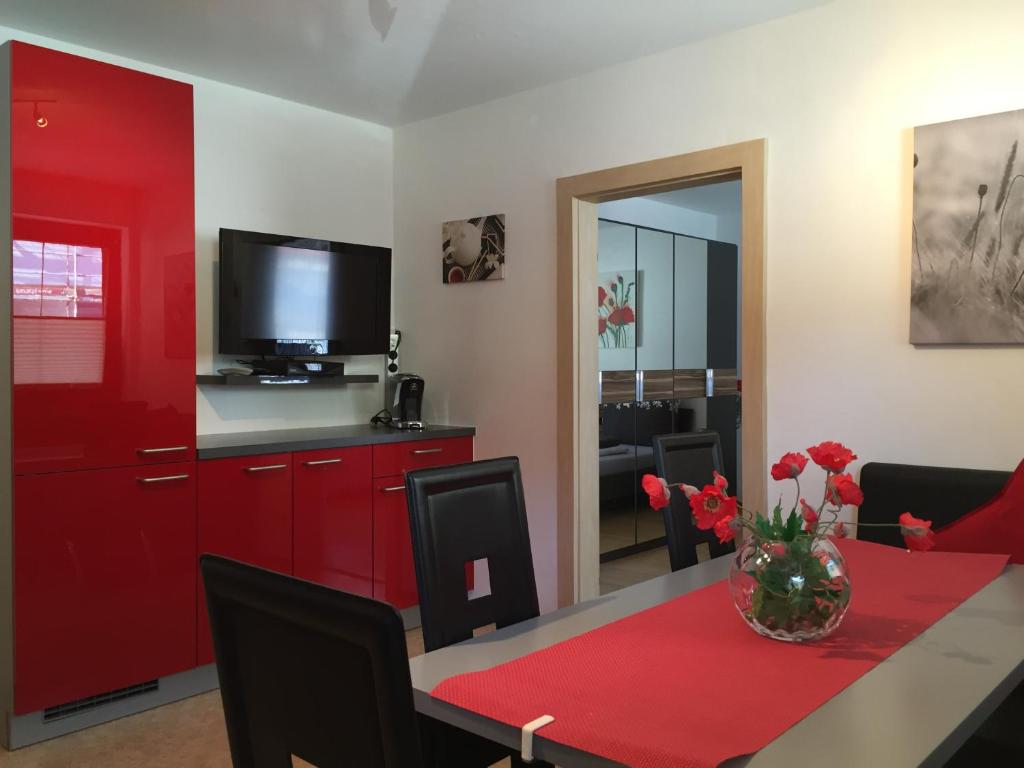 RietzFerienwohnung Familie Meinschad的一间用餐室,配有红色橱柜和一张桌子及一台电视
