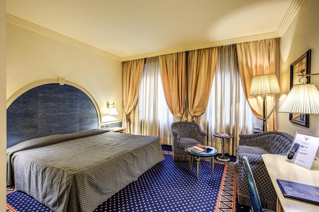 米兰奥瑞伽酒店的酒店客房,配有一张床和两把椅子