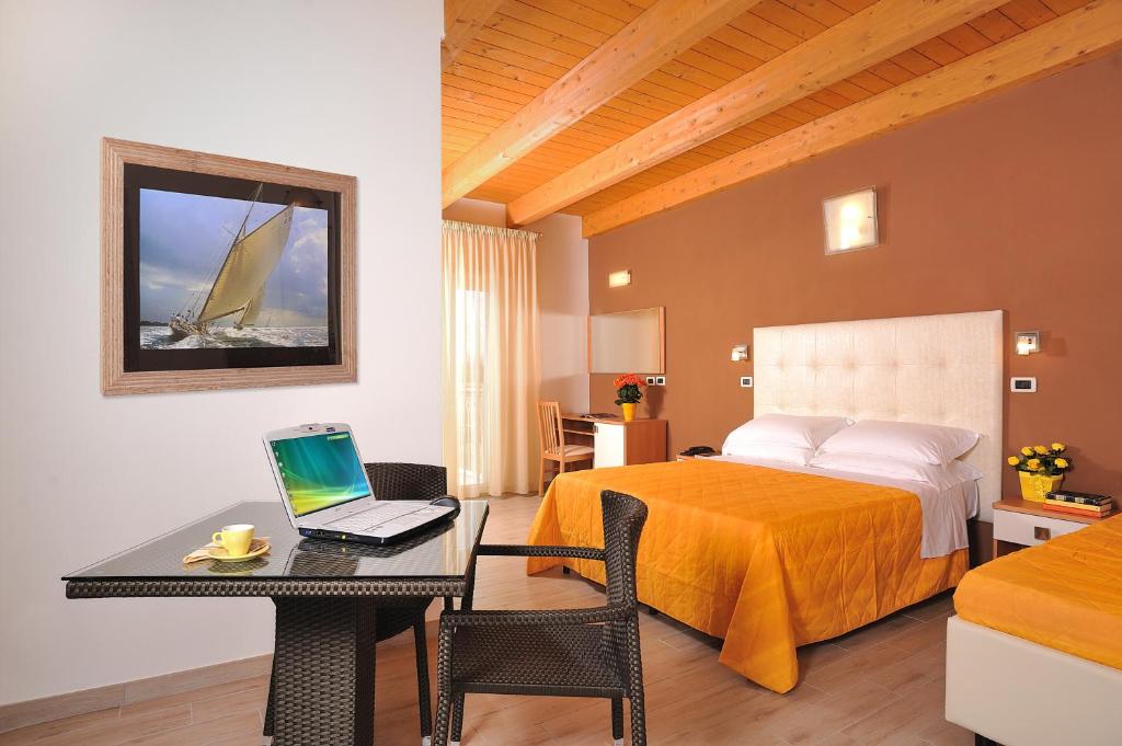 切塞纳蒂科法沃尔利塔酒店的酒店客房配有一张床铺和一张书桌上的笔记本电脑
