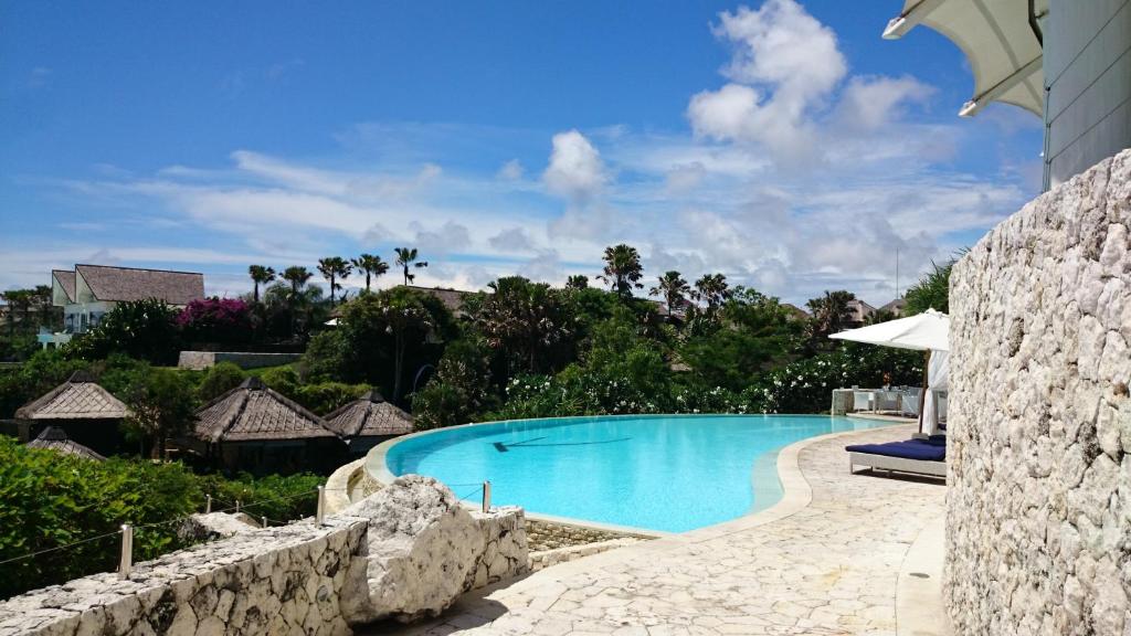 乌鲁瓦图Boutique hotel villa Cantik的一座拥有石墙的度假村内的游泳池