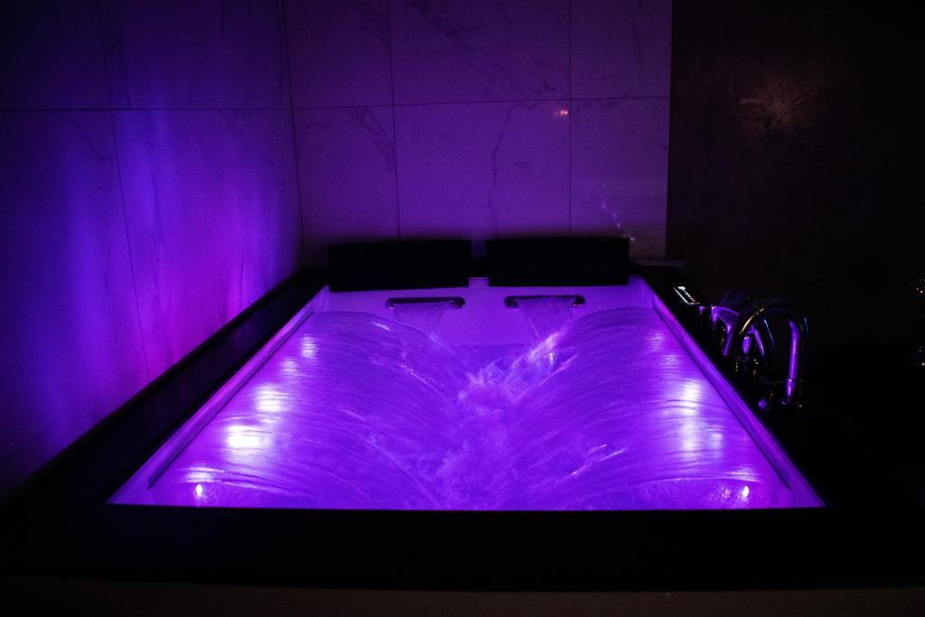 欧丹库尔Dreamspa的客房内的紫色浴缸,配有两把椅子