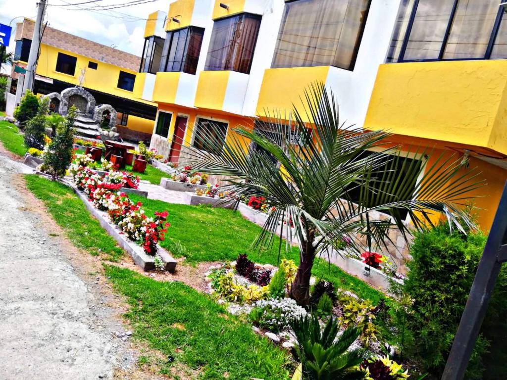 塔巴贝拉Hostal Mariscal Sucre的院子里有鲜花和棕榈树的建筑