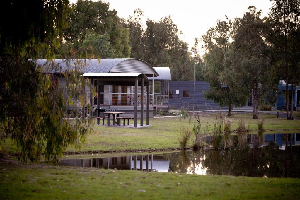 莫阿马Tasman Holiday Parks - Moama on the Murray的水体旁的一座带野餐桌的建筑