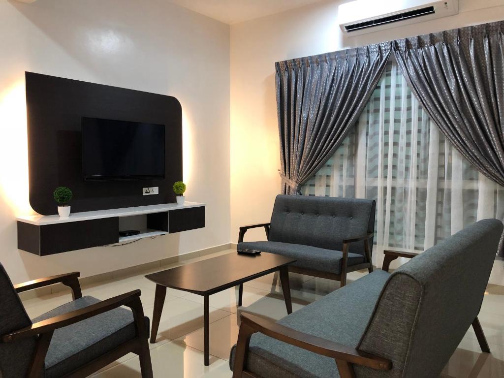 瓜拉雪兰戈Family homestay的客厅配有电视、2把椅子和1张桌子