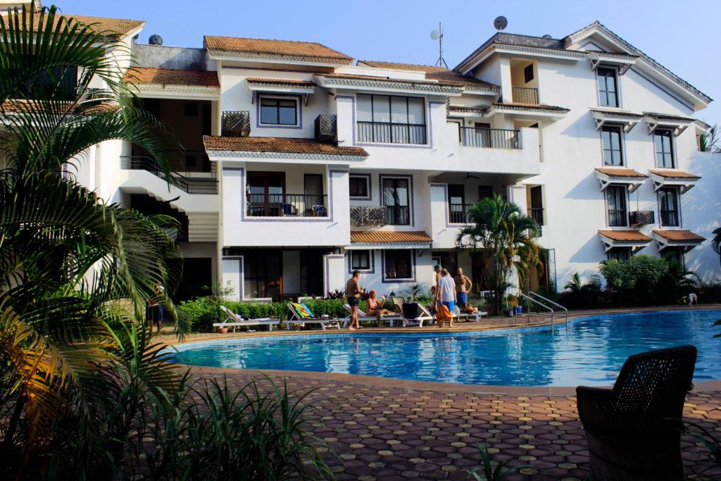 阿伯来Susegad Suites Goa Apartments & Villas Riviera Hermitage Arpora的大楼前设有游泳池的酒店