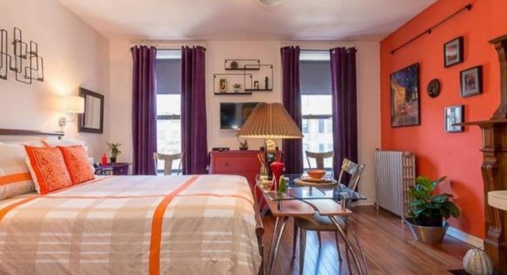 纽约Fabulous Fully Furnished Studio Minutes From Times Square!的一间卧室设有橙色的墙壁、一张床和一张桌子