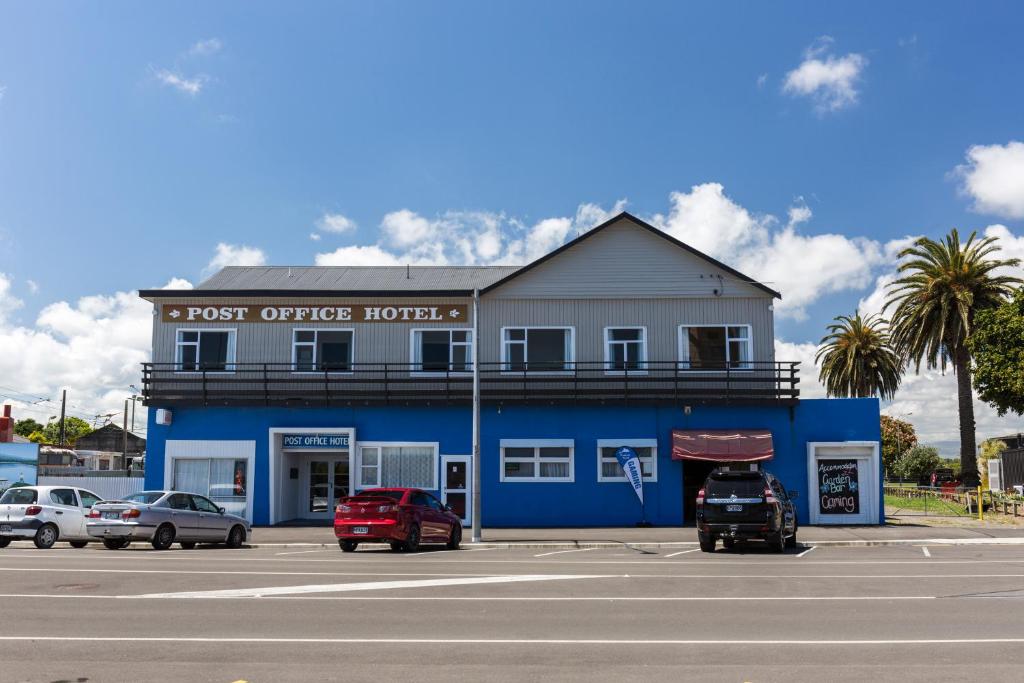 Foxton邮局酒店 的一座蓝色的建筑,前面有汽车停放