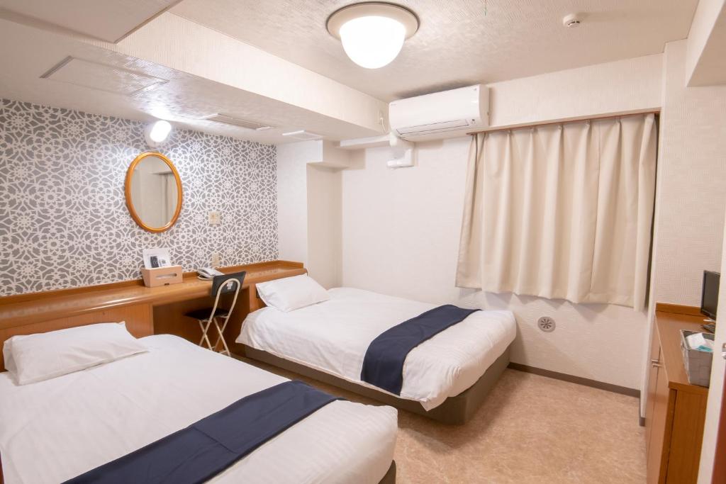 川崎Kawasaki Station Inn的酒店客房,设有两张床和镜子
