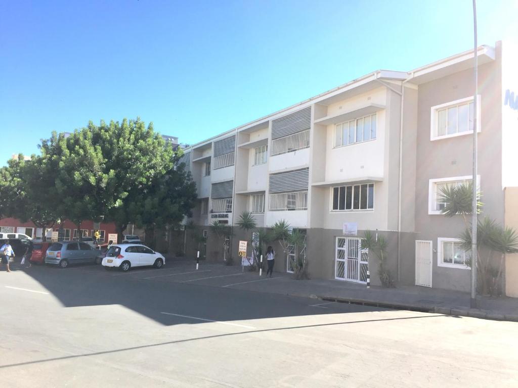 温特和克Stern self catering apartments的停车场内有车辆停放的公寓大楼