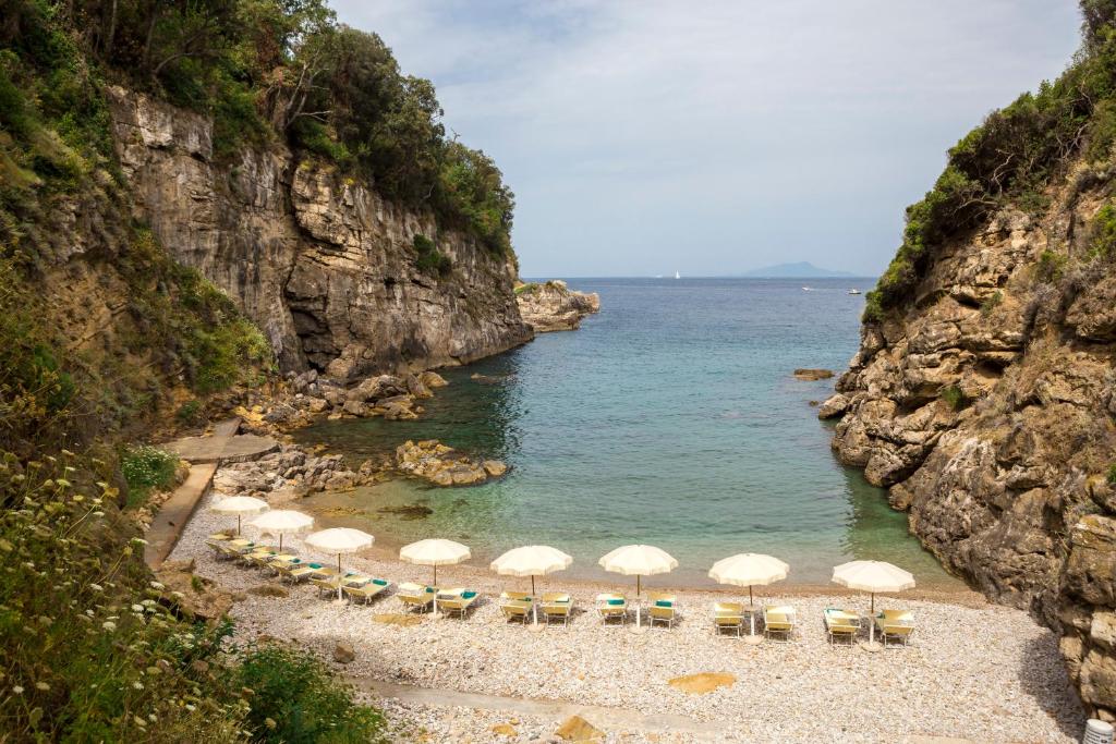 索伦托乔凡娜瑞加纳酒店的海滩上设有遮阳伞和椅子,还有大海