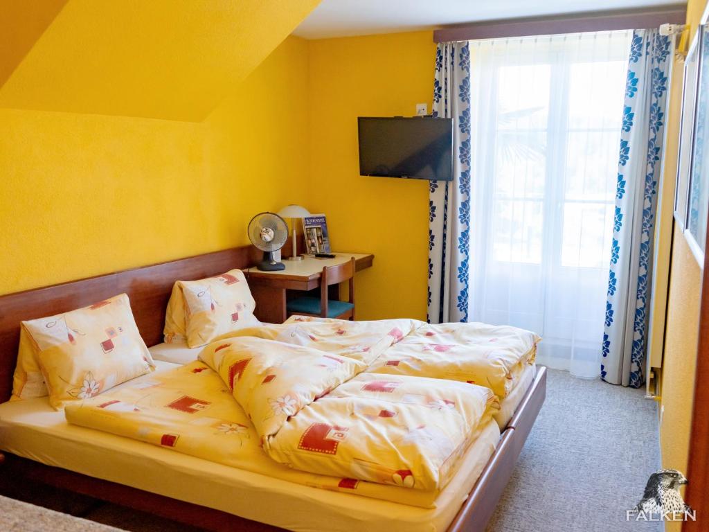 弗劳恩费尔德Gasthof zum Falken的一间卧室设有一张黄色墙壁和窗户的床