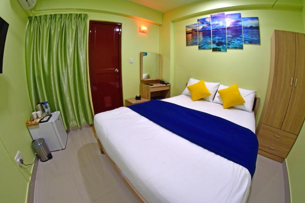 马累Tourist Inn的一间卧室配有一张大床,提供黄色和蓝色的枕头