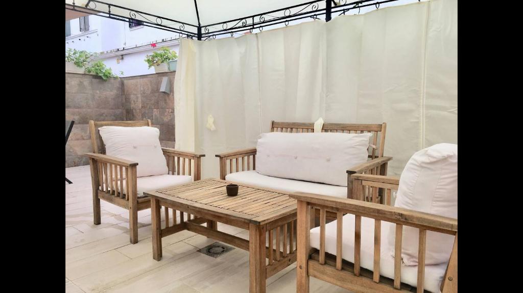 塞维利亚Apartamento Los Naranjos de Santa Justa的庭院配有两把椅子和一张带枕头的桌子。