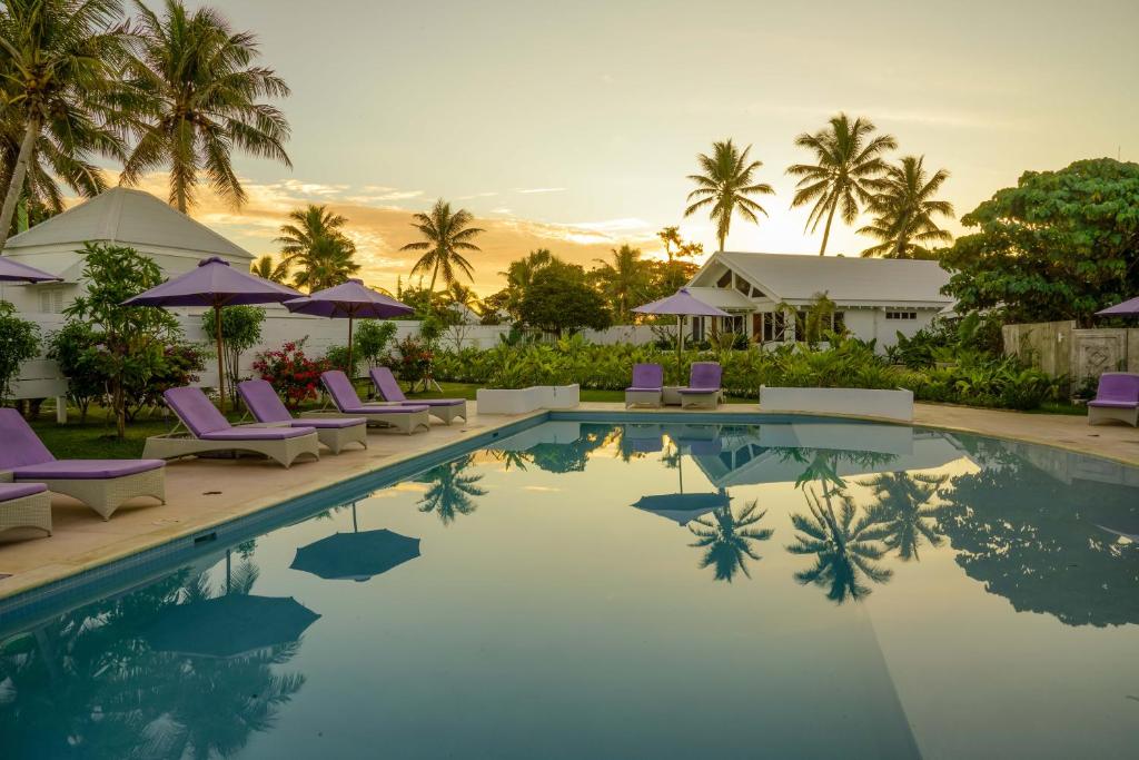 维拉港塔玛姆海滩酒店的度假村的游泳池配有椅子和遮阳伞