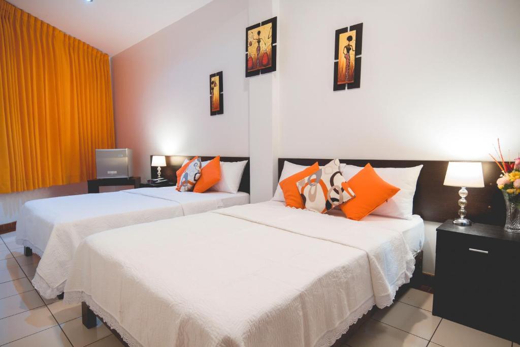 塔拉波托Hotel Fatima Inn的配有橙色枕头的酒店客房内的两张床