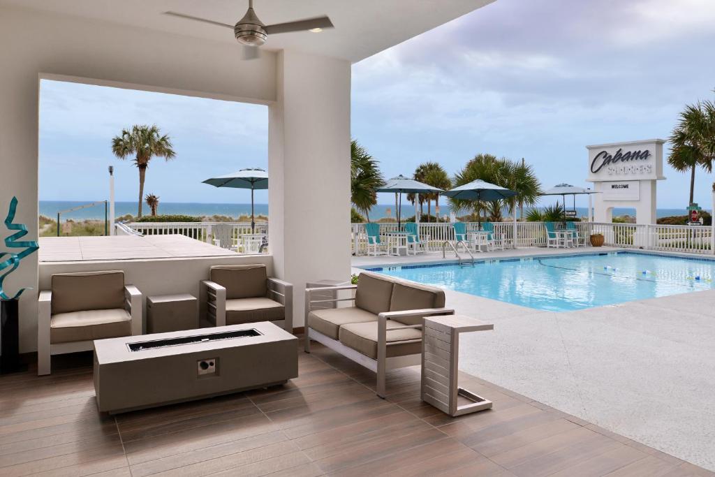 默特尔比奇Cabana Shores Hotel的一座带桌椅的游泳池以及一座建筑
