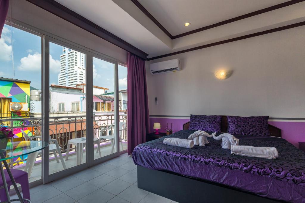 芭东海滩Grand Orchid Inn Patong beach的一间带紫色床的卧室和一个阳台