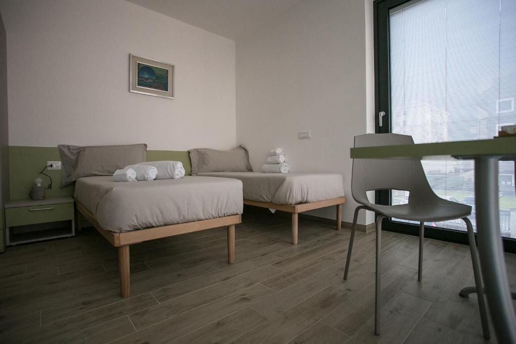 蒂拉诺B & B Il sorriso的一间设有两张床、一张桌子和一把椅子的房间