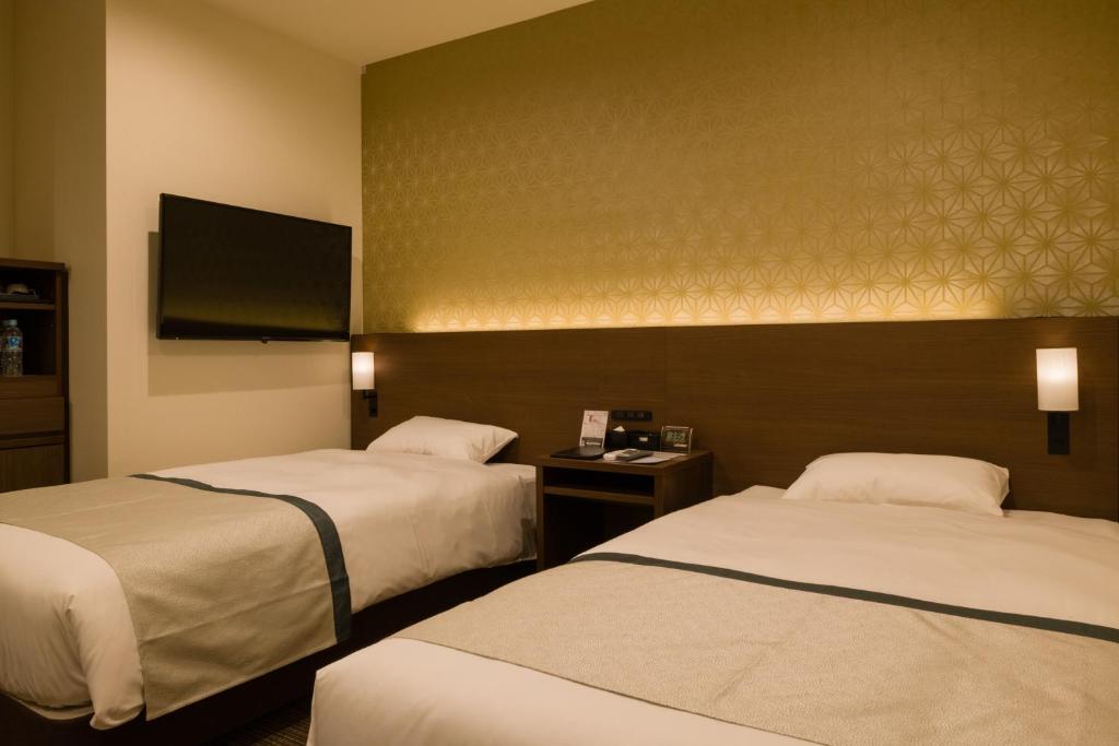 东京Tosei Hotel Cocone Ueno的酒店客房设有两张床和一台平面电视。