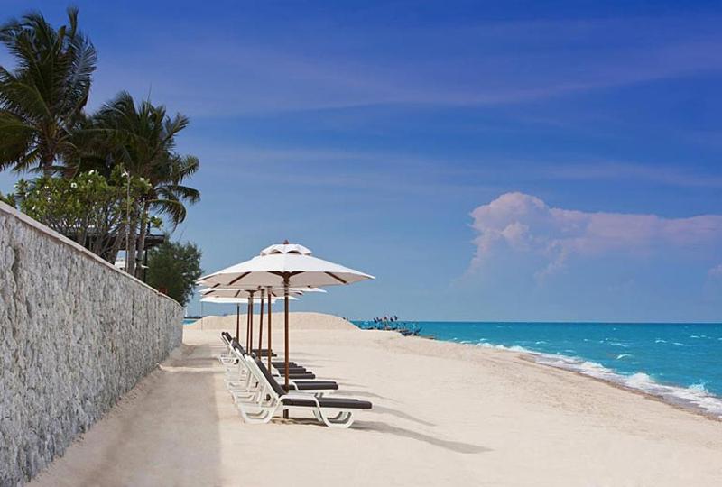 七岩Hua Hin Blue Lagoon的海滩上设有椅子和遮阳伞,大海