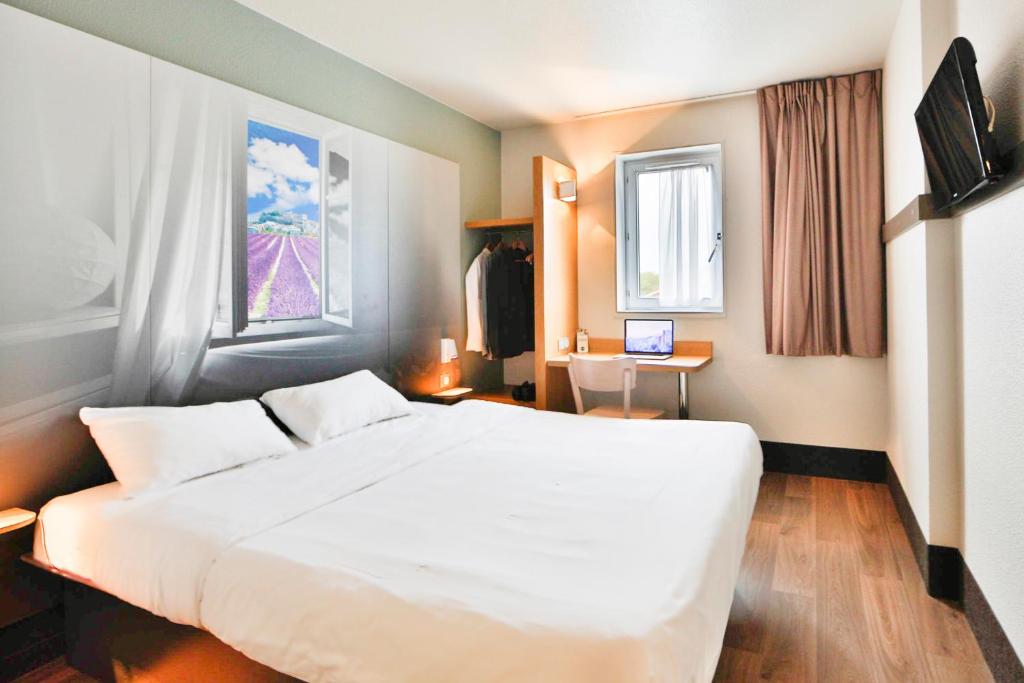 莱斯托雷特斯B&B HOTEL Montélimar Nord的卧室配有一张白色大床和一张书桌