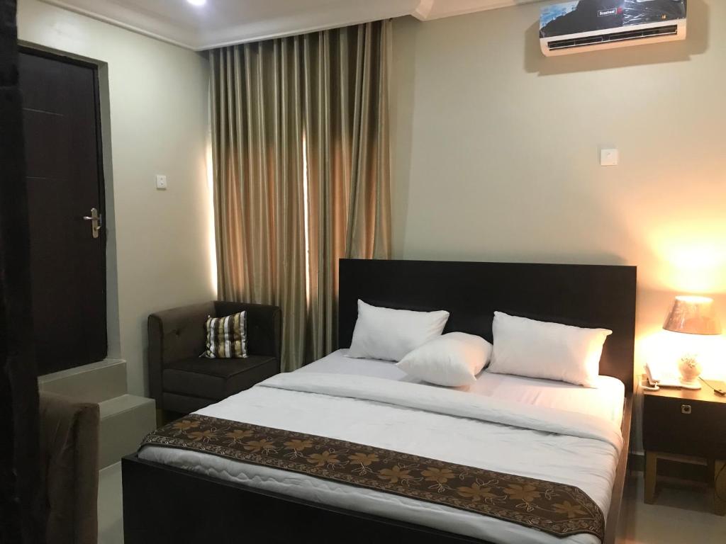 伊凯贾Choice Suites II的一间卧室配有一张带白色床单和椅子的床