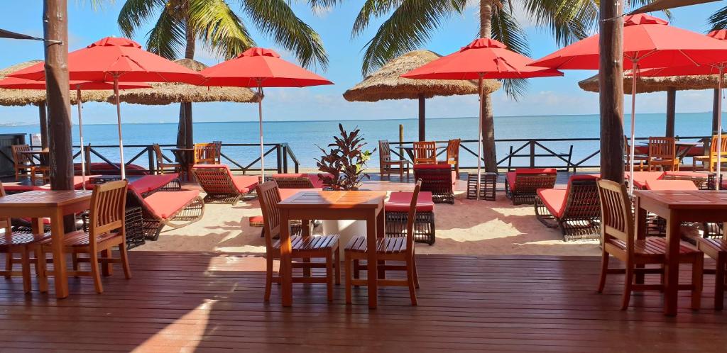 南迪斐济威洛艾洛海滩华美达酒店 的海滩上带桌椅和遮阳伞的甲板