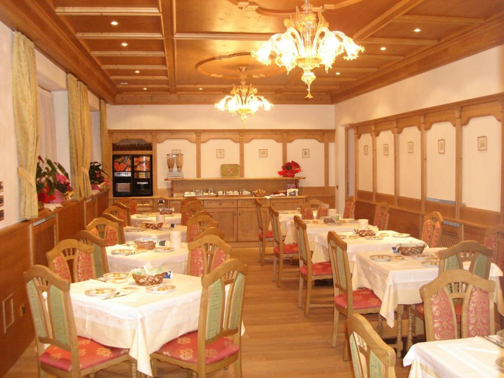 奥伦佐卡多利Albergo Garnì Ajarnola的餐厅配有白色的桌椅和吊灯