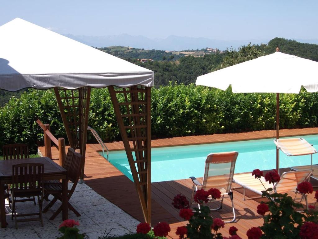 BossolascoBricco di Sant' Eufemia的一个带桌子和遮阳伞的庭院和一个游泳池