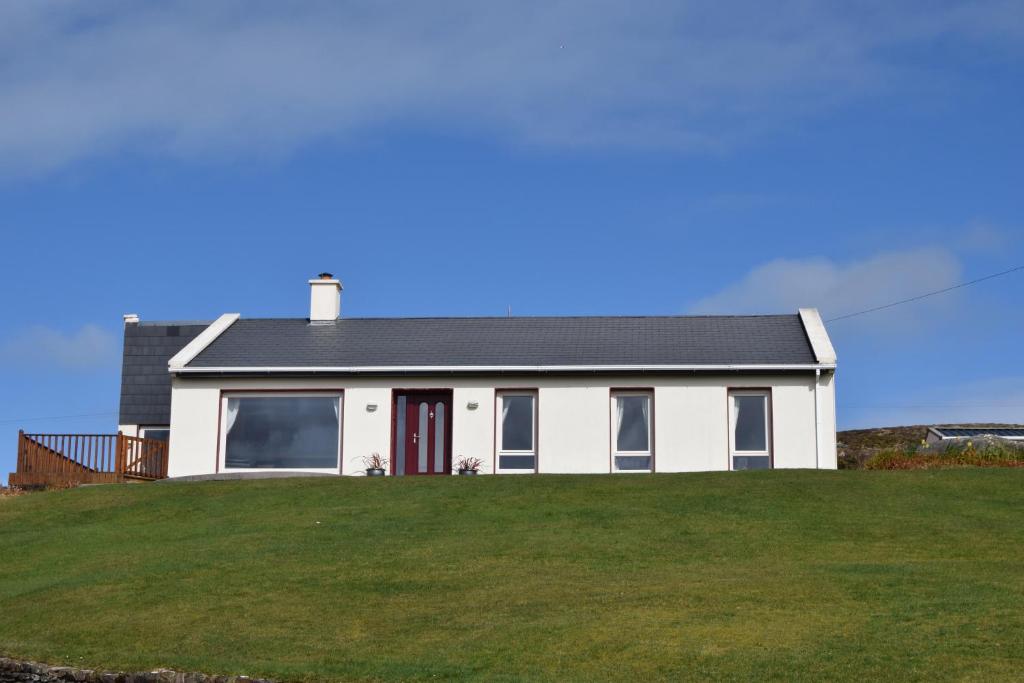丁格尔Ard na Carraige, Ventry Holiday Home的草山顶上的白色房子