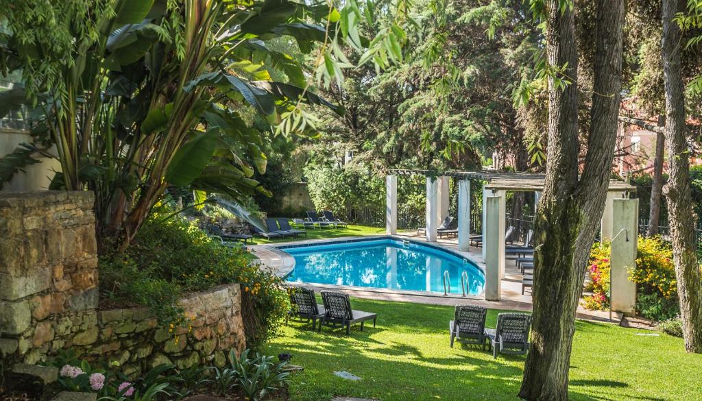 卡斯卡伊斯Casa Vela Boutique House的庭院内的游泳池,带椅子和树木