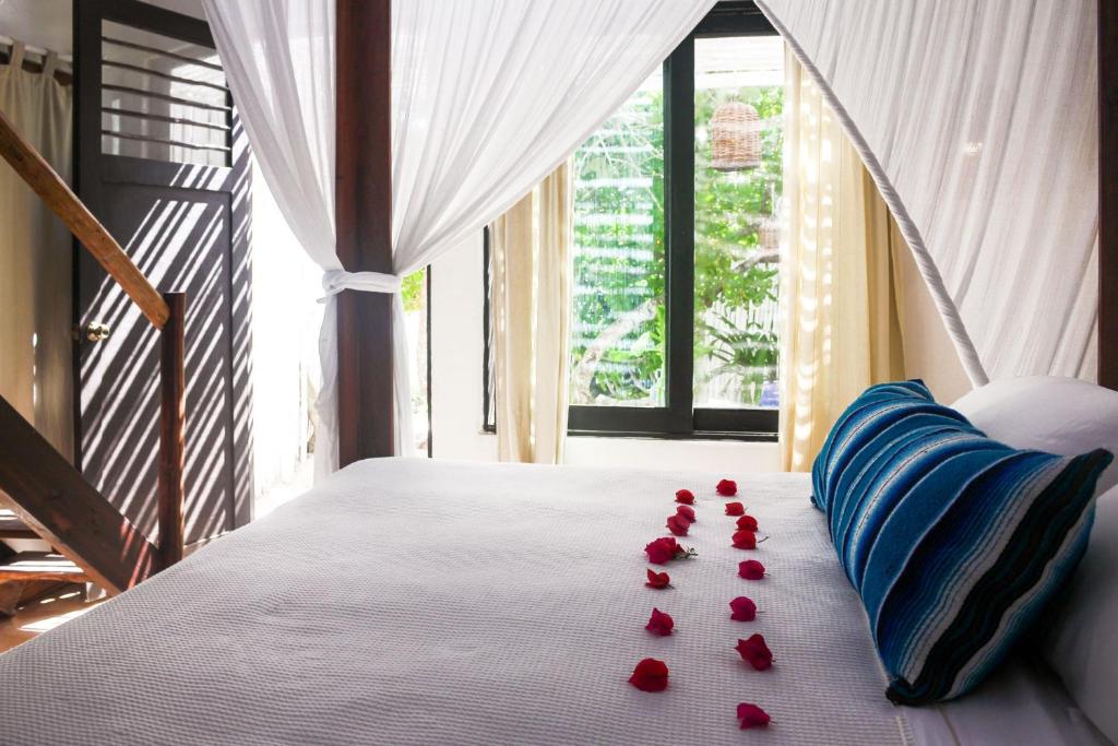 图卢姆比奥莱塔酒店的一张床上有红色玫瑰花瓣的床