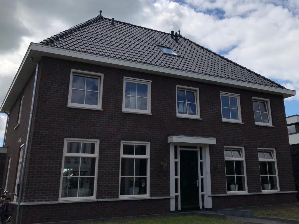 阿尔滕B&B nancy in holland的一间棕色砖屋,设有白色窗户和屋顶