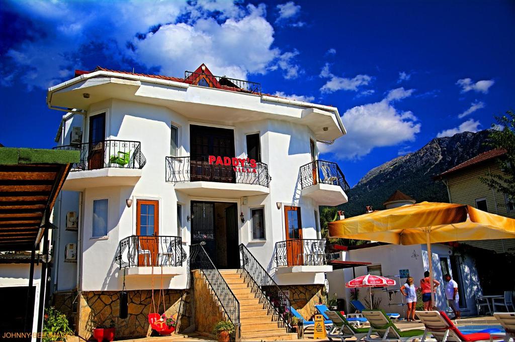 厄吕代尼兹Paddys Apartments Ovacık的带阳台和遮阳伞的白色建筑