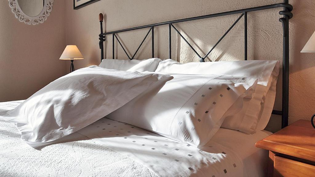 圣洛伦索-德莫鲁尼斯Casa Rural Rebost的白色的床、白色床单和枕头