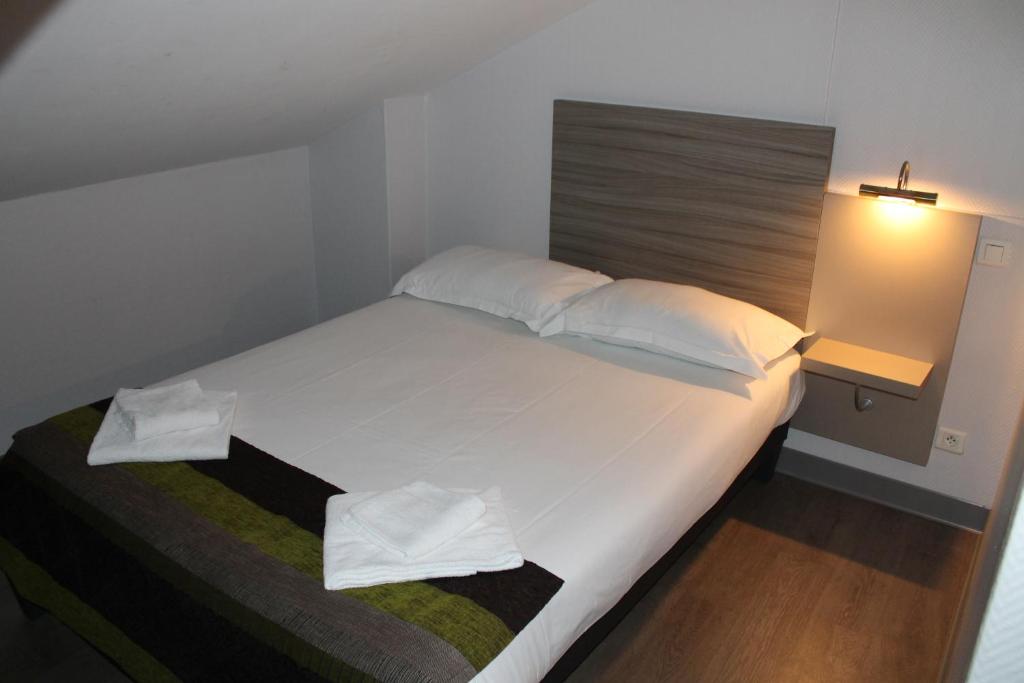 苏斯通Hôtel du Centre的卧室配有一张带白色床单和枕头的大床。