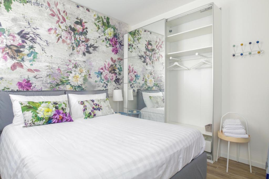 博洛尼亚Charming and cosy apartment的卧室配有白色的床铺,墙上挂着鲜花