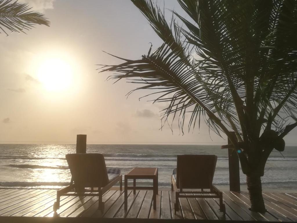 普拉亚多斯卡内罗斯Carneiros Paradiso的海滩上的两把椅子和一张桌子以及一棵棕榈树