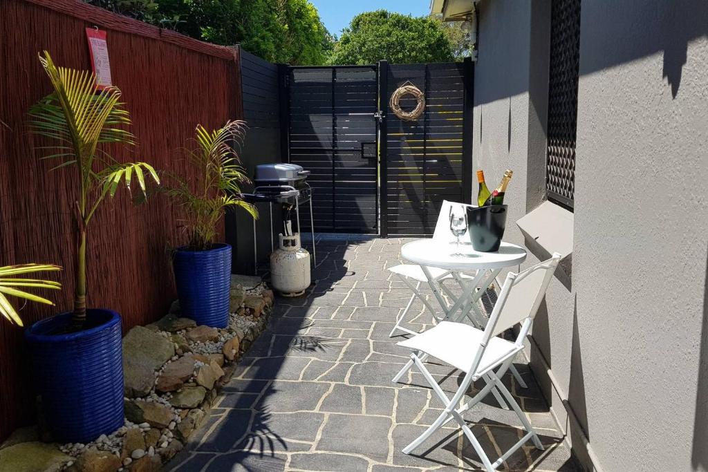 悉尼Seadreams, Maroubra的庭院设有两把椅子和一张桌子,种有植物