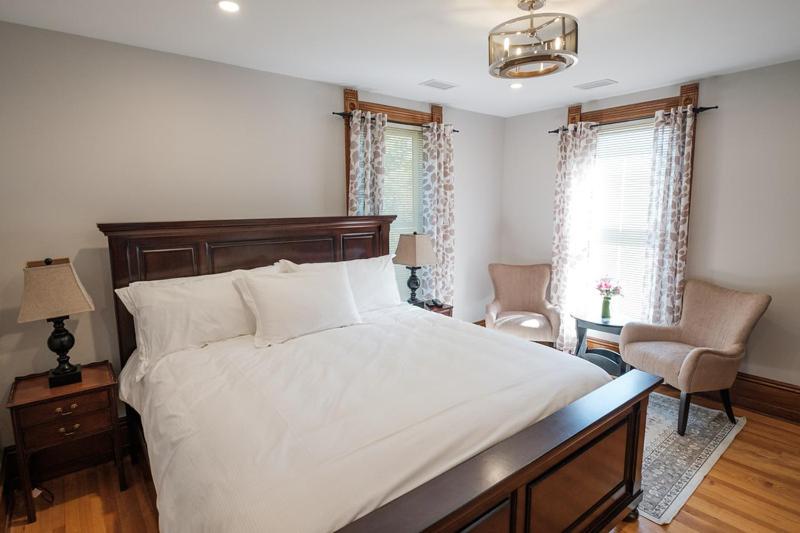WestportThe Victorian Luxury Suites的卧室配有一张白色大床和一把椅子