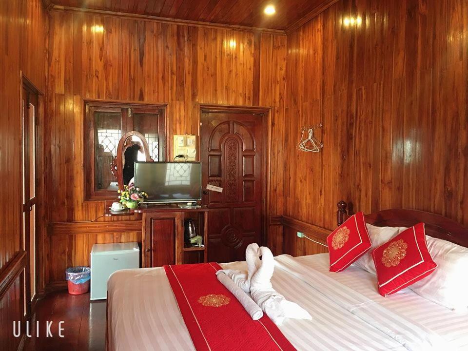 琅勃拉邦苏提考恩1号酒店的一间卧室配有一张带木墙的床和电视。