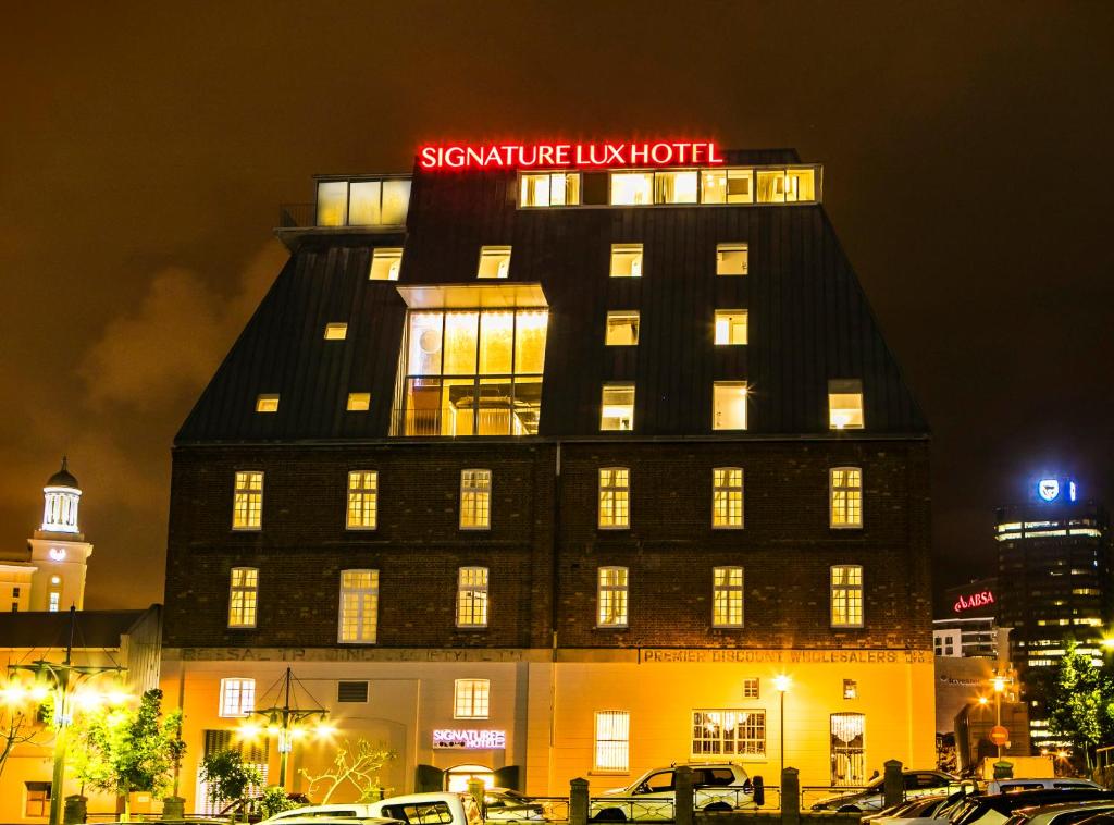开普敦Signature Lux Hotel by ONOMO, Waterfront的上面有 ⁇ 虹灯标志的建筑
