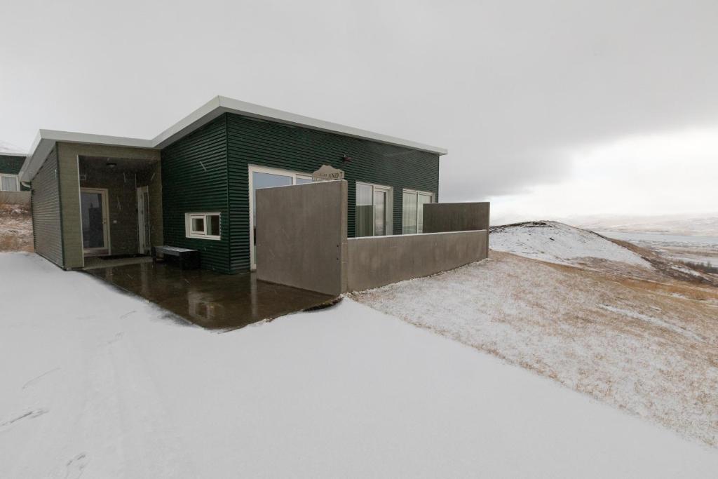 阿克雷里Hrimland Cottages的雪覆盖的山顶上的绿色房子