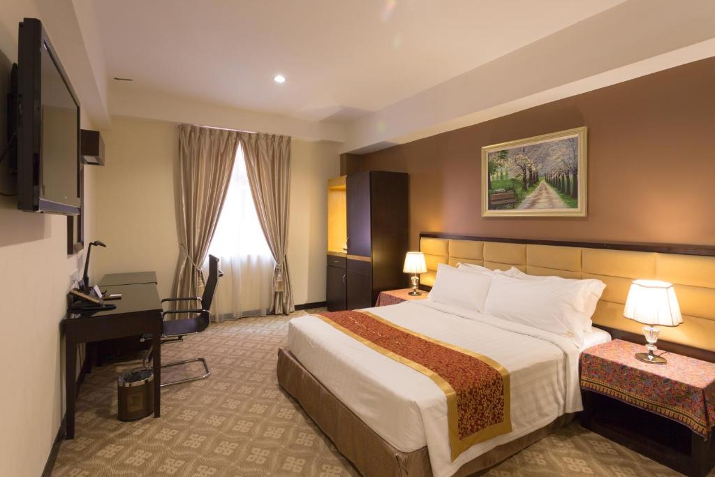 马六甲霍尔马克皇冠酒店的酒店客房设有一张大床和一张书桌。