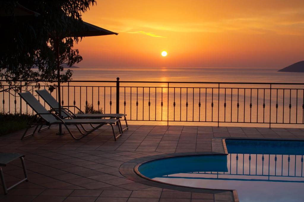 阿依亚埃夫菲亚佛蒂尼酒店的海洋上的日落,带椅子和游泳池