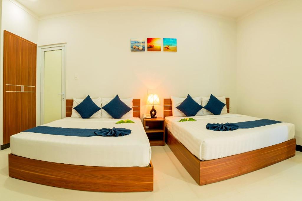 美奈PHAM GIA HOTEL Mui Ne的一间卧室配有两张带蓝色枕头的床