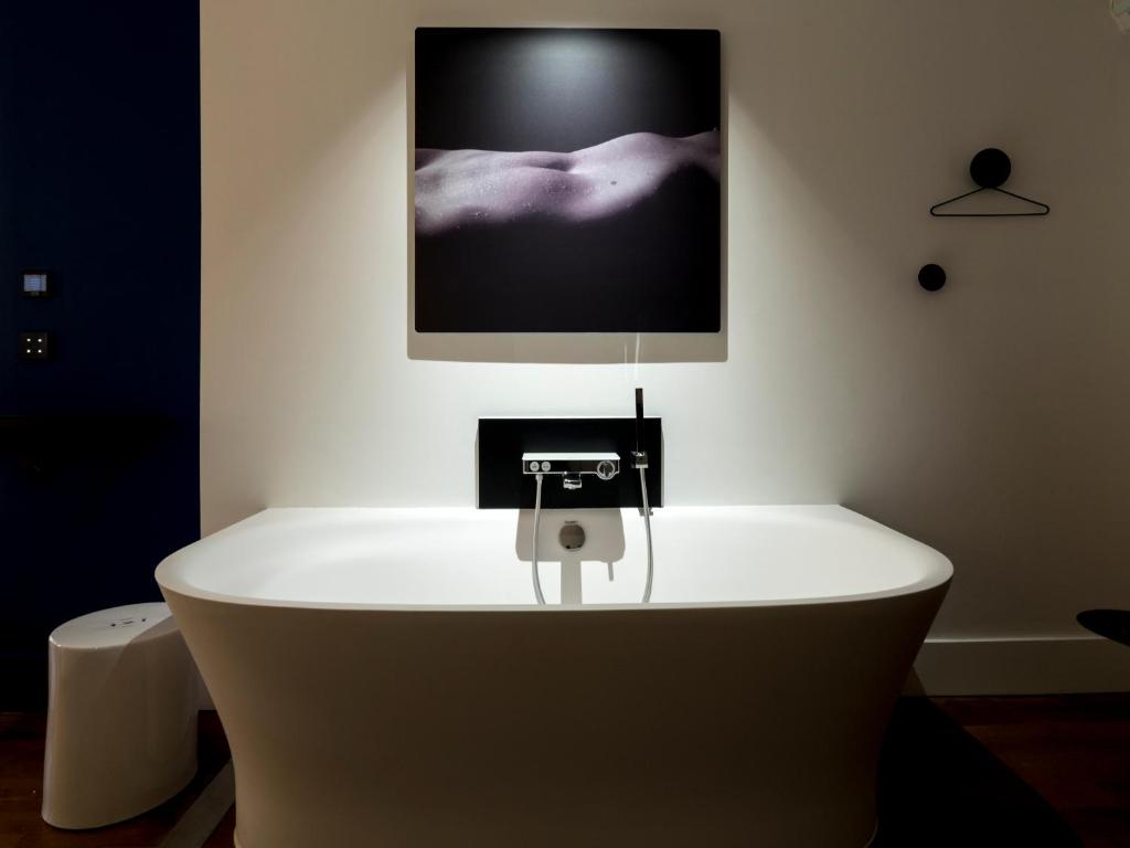 里昂MiHotel Vieux Lyon的浴缸位于墙上的电视房