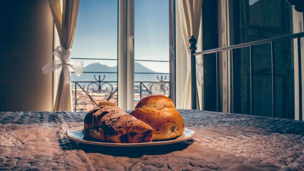 那不勒斯培欧尼亚住宿加早餐旅馆的桌子上一盘面包,有窗